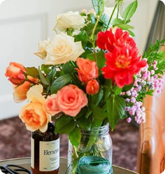Vase with a mix of red, orange, and pink flowers on a table.
