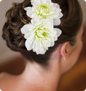 Woman's hair styled with two white flowers.