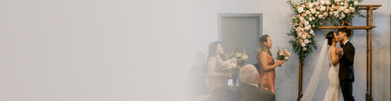 Couple kissing at their wedding ceremony with guests watching.
