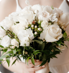 A bride holding a bouquet of white roses and greenery.